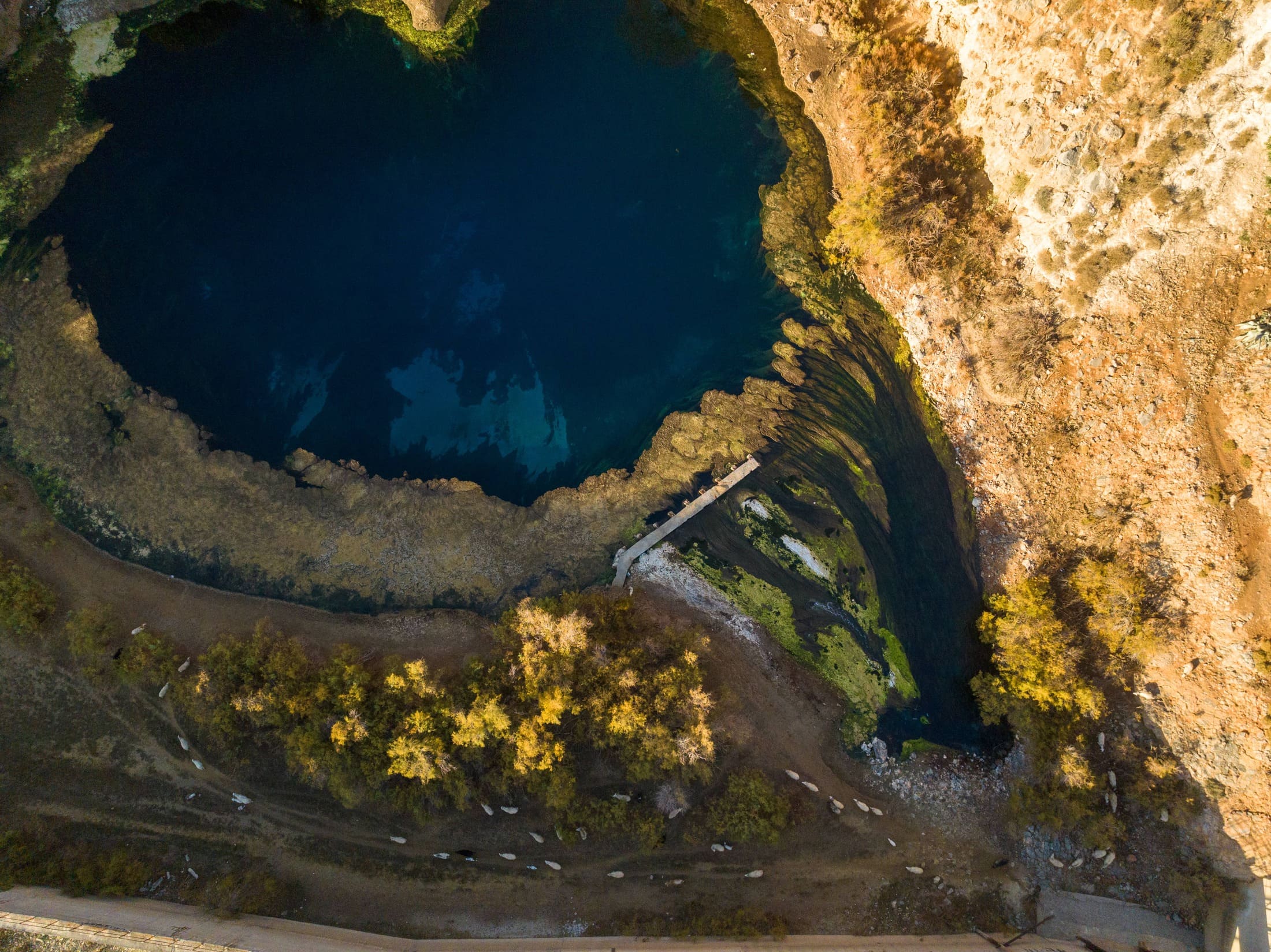 Aerial view of a deep blue lake between rocks and autumn trees